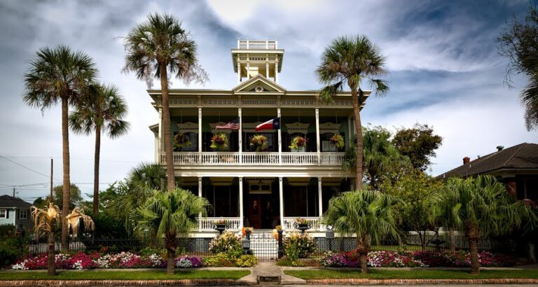 Stunning view of a historic mansion with lush gardens and palm trees in Galveston, Texas.